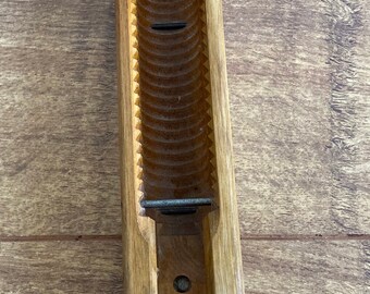 May include: A wooden shuttle with a pointed tip and a grooved interior. The shuttle has a metal latch and a small hole on the side.