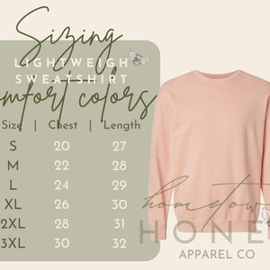 Op de afbeelding: Een lichtroze sweatshirt met ronde hals naast een maattabel. De tabel vermeldt de maten S tot en met 3XL met bijbehorende borst- en lengtematen in inches. De tekst bevat Sizing, Lightweight Sweatshirt, Comfort Colors en Hometown Honey Apparel Co, versierd met kleine bijenillustraties.