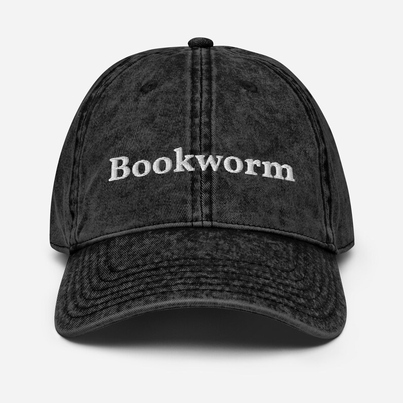 Puede incluir: Una gorra de b&eacute;isbol de algod&oacute;n vintage lavada en negro con la palabra "Bookworm" bordada en blanco en la parte delantera.