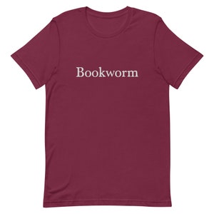 May include: A maroon t-shirt with the word "Bookworm" printed in white on the front.