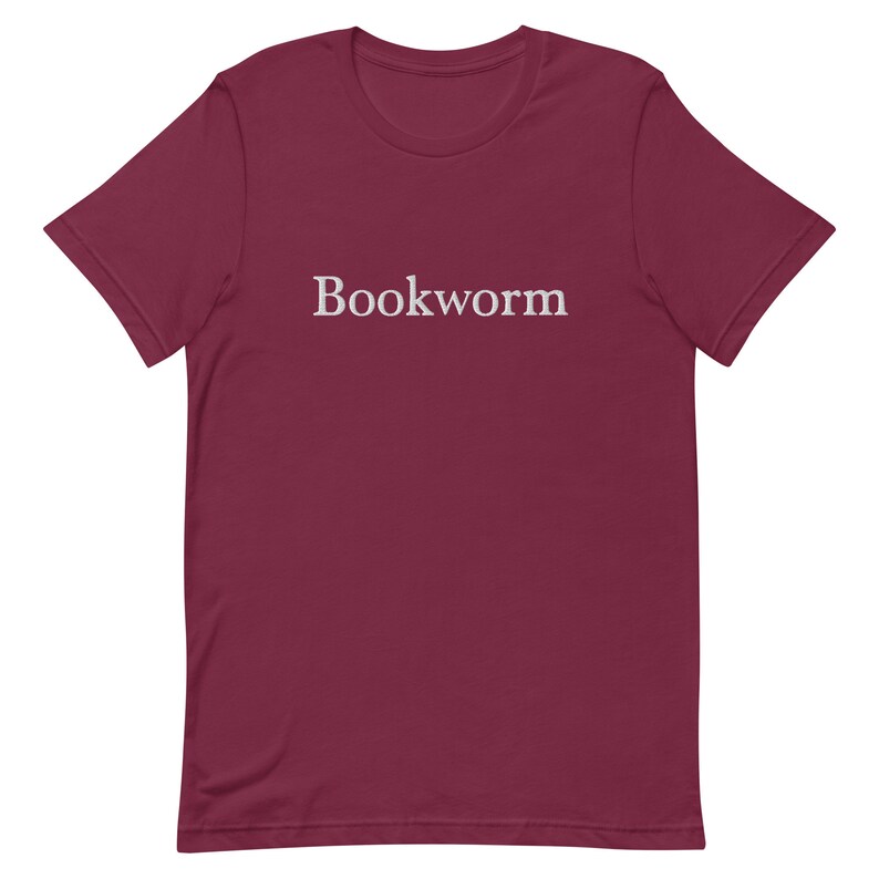 May include: A maroon t-shirt with the word "Bookworm" printed in white on the front.