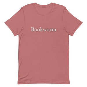 May include: A pink t-shirt with the word "Bookworm" printed in white on the front.