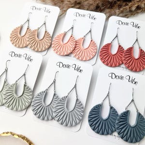 Op de afbeelding: Een set van drie keramische mokken met een gespikkelde, matte afwerking. De mokken zijn in crème, lichtgrijs en donkergrijs. Elke mok heeft een eenvoudig, minimalistisch ontwerp.