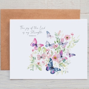 May include: A white card with a watercolor illustration of pink and purple butterflies and flowers. The text "The joy of the Lord is my strength. Nehemiah 8:10" is printed on the card.