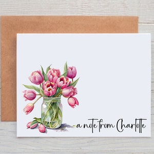 May include: A white card with a pink and green watercolor illustration of tulips in a glass jar. The text "a note from Charlotte" is printed at the bottom of the card.