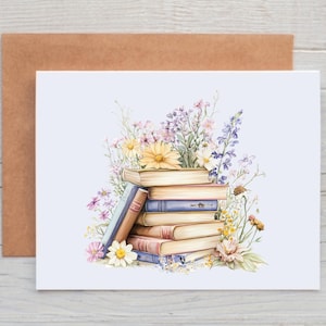 May include: A stack of vintage books with a floral arrangement of purple, pink, yellow, and white flowers. The books are arranged in a stack with the top book being a light blue color. The flowers are arranged around the books and are in full bloom.