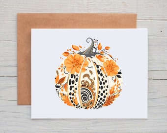 May include: A white pumpkin with black and brown spots and orange floral accents. The pumpkin is decorated with orange and brown leaves and flowers.