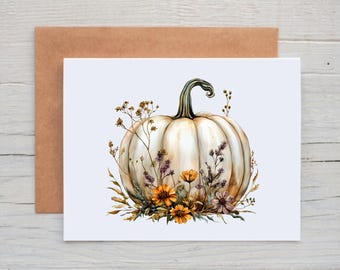 May include: A white pumpkin illustration on a greeting card, adorned with watercolor flowers in shades of orange, purple, and brown. The card is paired with a brown envelope, perfect for fall or autumn-themed occasions.