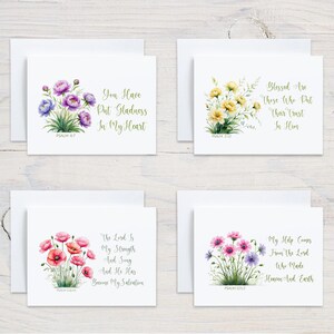 May include: Four white greeting cards with floral watercolor designs and inspirational quotes. Each card features a different flower arrangement in shades of purple, yellow, pink, and a mix of colors, with accompanying text in gold script.