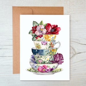 May include: A stack of four vintage teacups with floral patterns, topped with a bouquet of pink, red, and yellow flowers.