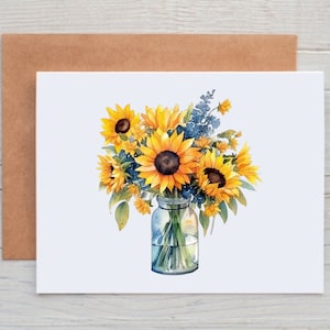 May include: A watercolor illustration of sunflowers in a glass jar on a white card. The sunflowers are yellow with brown centers, and blue flowers are interspersed. A brown envelope is behind the card. The image is a greeting card.