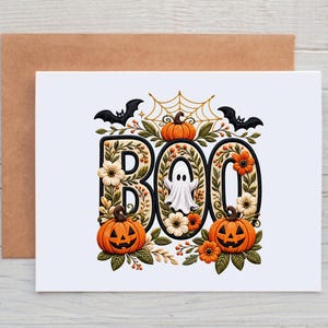 May include: A white greeting card featuring the word BOO in large black letters filled with orange pumpkins, white and orange flowers, and green leaves. A small white ghost sits inside the letter O, with a spiderweb, bats, and pumpkins above.