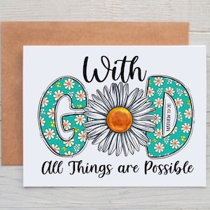 May include: A white card with a turquoise and white floral design that spells out the word "GOD" with a daisy in the center. The text "With God All Things Are Possible" is written below the design. The scripture reference "Matthew 19:26" is written on the right side of the design.