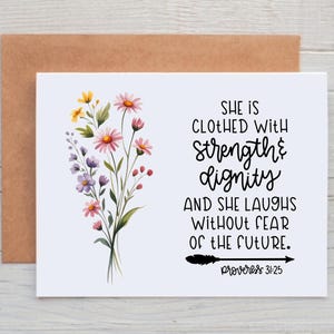 May include: A white greeting card with a watercolor floral design and the text "She is clothed with strength & dignity and she laughs without fear of the future." The card is paired with a brown envelope.