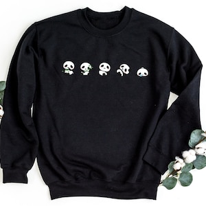 K&ouml;nnte beinhalten: Schwarzes Sweatshirt mit einer Reihe von f&uuml;nf Pandagesichtern, die auf der Vorderseite aufgedruckt sind. Jedes Panda hat einen anderen Ausdruck, darunter gl&uuml;cklich, traurig und &uuml;berrascht.