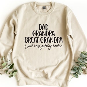 May include: A beige sweatshirt with black text that reads "Dad Grandpa Great-Grandpa I just keep getting better".
