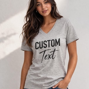A young woman with long brown hair wearing a grey t-shirt with the text "CUSTOM Text" printed on it.