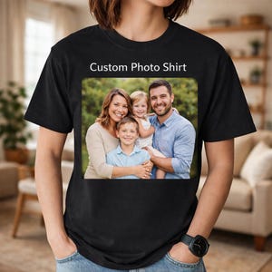 Op de afbeelding: Een zwart T-shirt met korte mouwen en de tekst Custom Photo Shirt in het wit gedrukt boven een rechthoekige kleurenfoto van een gezin van vier, bestaande uit een man, een vrouw, een jong meisje en een jongen, die samen buiten poseren.