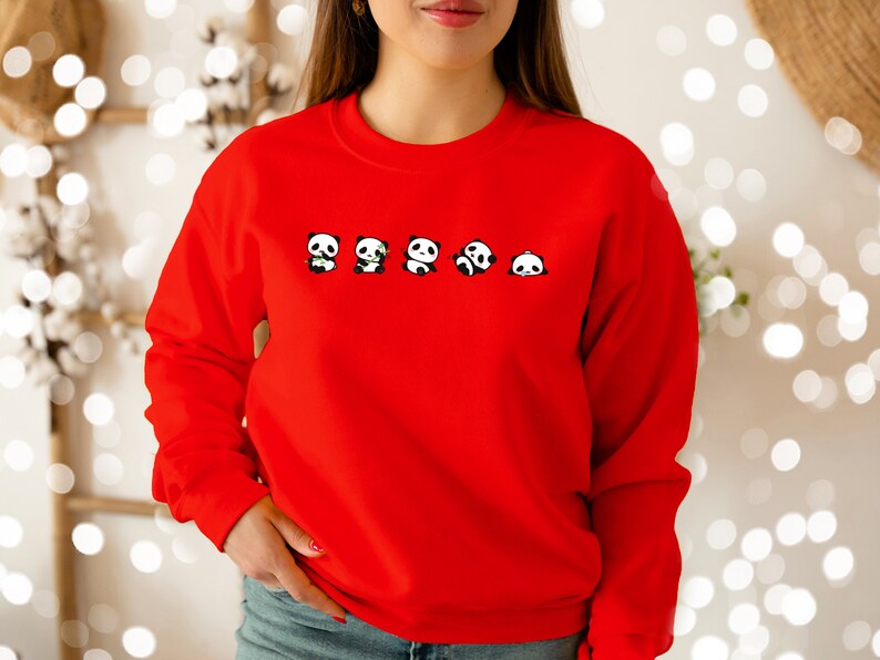 K&ouml;nnte beinhalten: Roter Pullover mit einem Aufdruck von f&uuml;nf Pandas, die Bambussprosse halten.