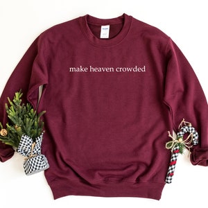 May include: Burgundy sweatshirt with the text "make heaven crowded" in white lettering.