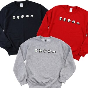 K&ouml;nnte beinhalten: Drei Sweatshirts mit einer Reihe von Pandas, die auf der Vorderseite aufgedruckt sind. Die Sweatshirts sind in Marineblau, Rot und Grau.