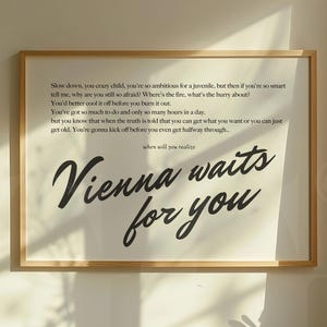 Op de afbeelding: Een ingelijste print met de tekst "Vienna waits for you" in sierlijk handschrift, vergezeld van een gedicht. De lijst is gemaakt van lichtgekleurd hout. De print hangt aan een muur.