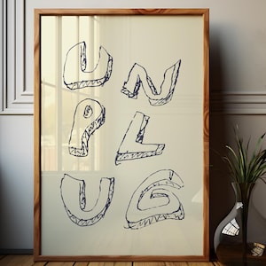 May include: A framed art print with the word "UNPLUG" in a handwritten style. The letters are outlined in dark blue on a cream-colored background. The frame is made of light brown wood, and the artwork is displayed on a wooden floor.
