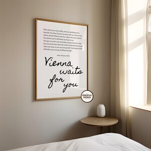 May include: A framed print with the words "Vienna waits for you" in a stylish script font. The print also includes lyrics from a song. The frame is a light brown color, and the background is white.