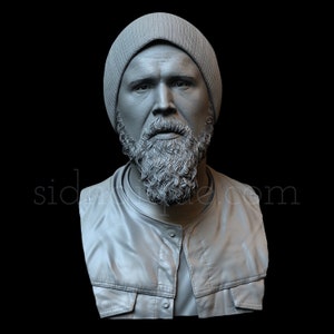 Puede incluir: Un busto de escultura gris de una persona que lleva un gorro y una chaqueta. La persona tiene barba y una expresión seria.