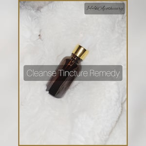 May include: A brown glass bottle with a gold cap and white dropper, labeled "Cleanse Tincture Remedy." The bottle is set against a fluffy white background. The text "144k Apothecary" is in the top right corner.