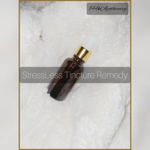 May include: A brown glass bottle with a gold lid and a white dropper. The bottle is labeled "StressLess Tincture Remedy".