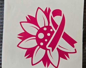 Könnte beinhalten: Ein pinkfarbenes Sonnenblumen-Design mit einem pinkfarbenen Band, das das Bewusstsein für Brustkrebs symbolisiert. Die Sonnenblume hat weiße Blütenblätter und eine pinkfarbene Mitte mit weißen Punkten. Das Band ist mit der Blume verschlungen.