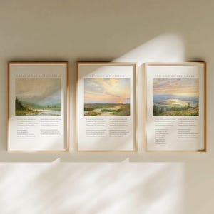 May include: Three framed landscape art prints with gold frames. The prints feature scenic paintings of mountains, rivers, and sunsets. Each print has text at the top and bottom. The text on the first print reads "GREAT IS THY FAITHFULNESS". The second print reads "BE THOU MY VISION". The third print reads "TO GOD BE THE GLORY".