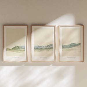 Puede incluir: Juego de tres láminas artísticas de paisajes enmarcadas. Cada lámina presenta una pintura a la acuarela de una cordillera en tonos verdes y azules sobre un fondo beige. Cada lámina tiene una cita en la parte inferior.