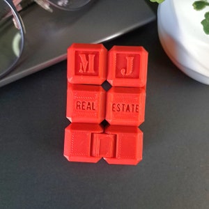 May include: Red plastic blocks spelling out "M.J. REAL ESTATE" in a bold, white font.