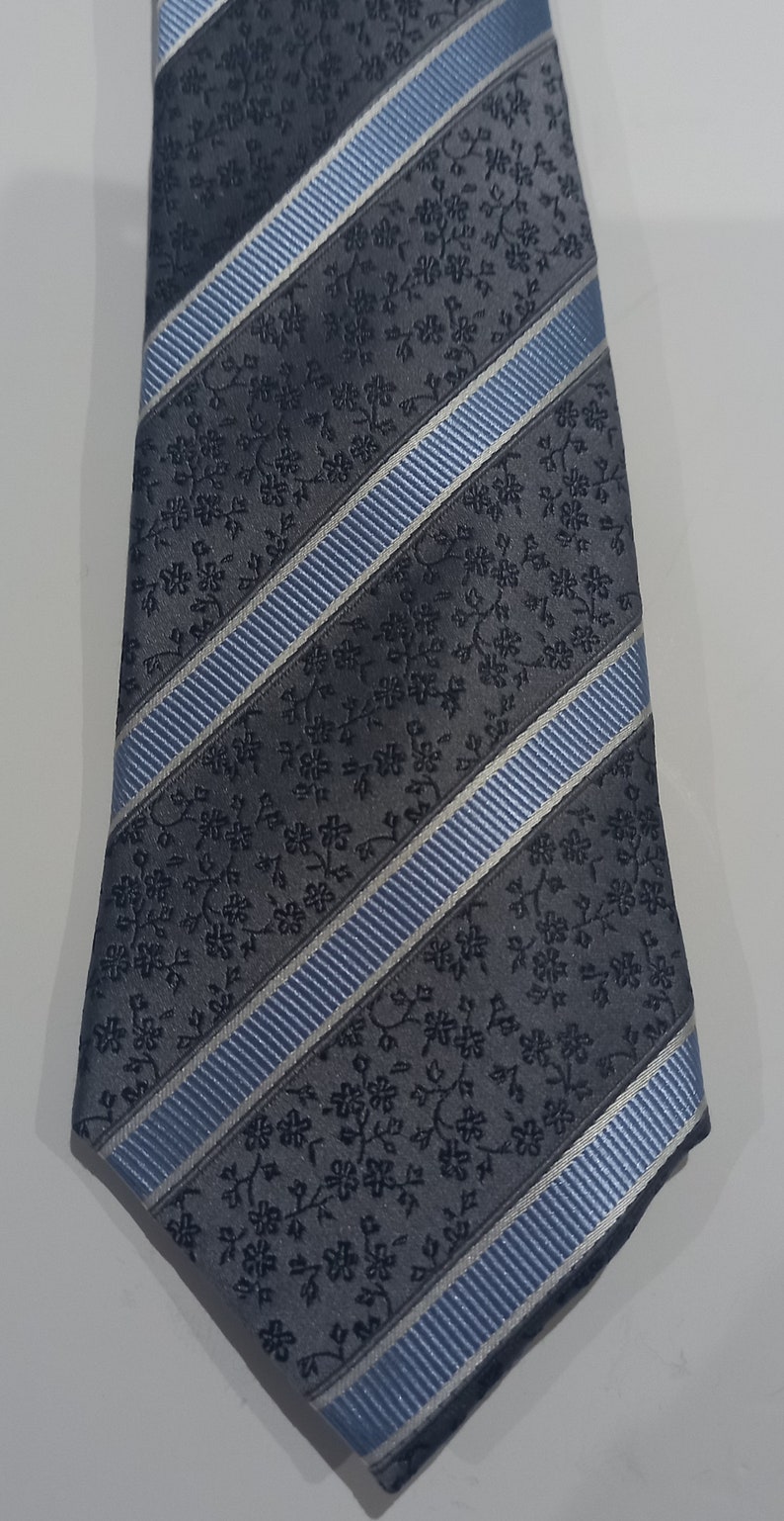 May include: A gray and blue patterned tie with a diagonal stripe design. The tie has a floral pattern.