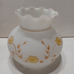 Puede incluir: Pantalla de lámpara de vidrio blanco con un borde superior festoneado y un diseño floral en tonos marrones y amarillos.