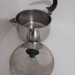 May include: A stainless steel teapot with a black handle and a matching lid. The teapot has a spout and a round body.