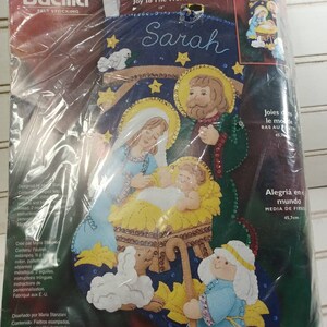 May include: A felt stocking kit featuring a nativity scene with Mary, Joseph, and baby Jesus. The kit includes felt pieces, sequins, beads, and instructions. The stocking is 18 inches long and is titled "Joy to the World".