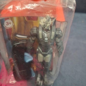 May include: A gray and silver action figure of Iron Man in a clear plastic bag with a red and gold cardboard box. The box has a 3+ age recommendation.