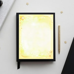 May include: A black notebook with a yellow and white lined paper insert, a gold pen, and a black notebook are on a white surface. The lined paper has a yellow watercolour wash and star accents. Gold star-shaped confetti is scattered around.