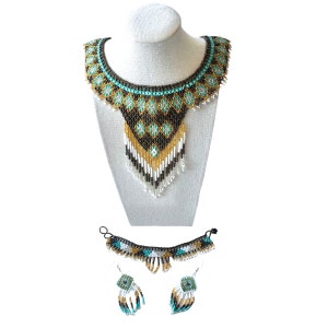 May include: A beaded necklace and matching earrings set. The necklace features a bib design with turquoise, gold, black, and white beads. The earrings have square turquoise and white beaded designs. The jewelry is displayed on a mannequin head.
