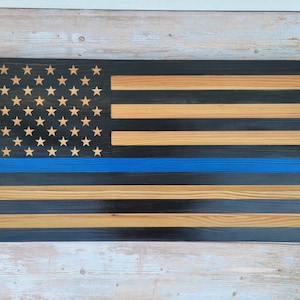 May include: Wooden American flag with a blue line, representing support for law enforcement. The flag is made of reclaimed wood and has a distressed finish.