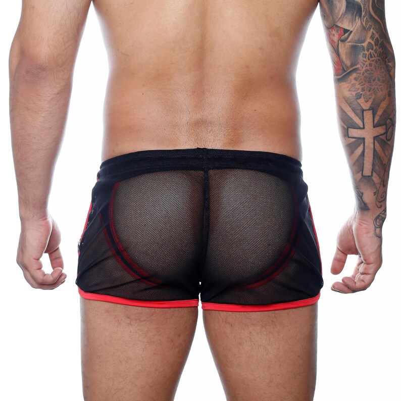 May include: Black mesh shorts with red trim and accents. The shorts have a drawstring waistband and a sporty design. The see-through fabric reveals the wearer's skin. The shorts are designed for athletic activities or casual wear.