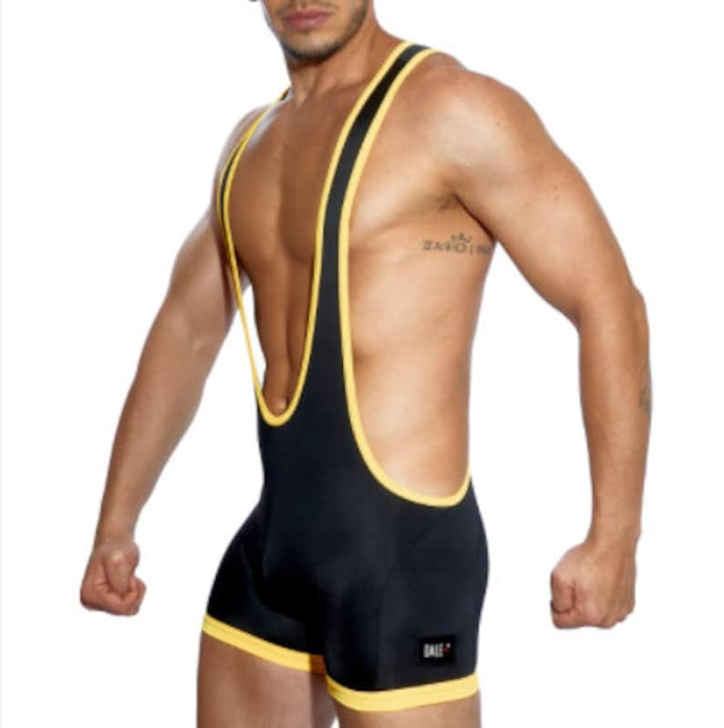 May include: Black singlet with yellow trim. The athletic garment features a scoop neck and a racerback design. The trim is visible around the neckline, armholes, and leg openings. The word "BALE" is printed on the lower left side.