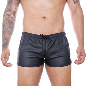 May include: Black athletic shorts with a drawstring waist and a small white square label on the side. The shorts have a smooth, matte finish and a black trim along the edges. The shorts are designed for athletic activities.
