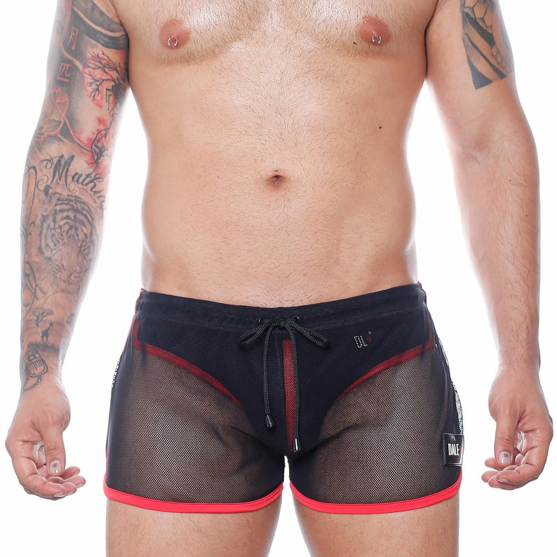 May include: Black mesh shorts with red trim and a drawstring waist. The shorts have a red vertical stripe down the front and a small logo on the side. The shorts are designed for swimwear.