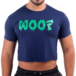 May include: Navy blue crop top with the word "WOOF" in bright green block letters. The shirt has short sleeves and a raw hem. The text is centered on the chest.