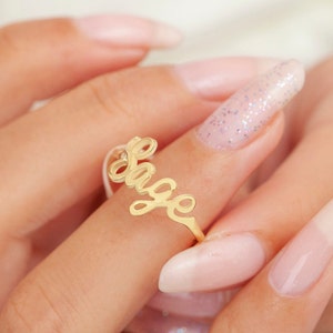 May include: A gold ring with the name "Sage" spelled out in cursive script.