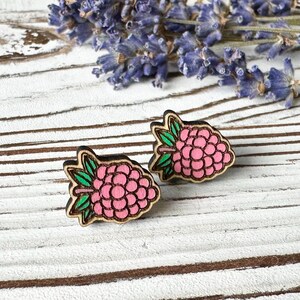 May include: A pair of wooden earrings shaped like raspberries. The earrings are painted pink with green leaves.